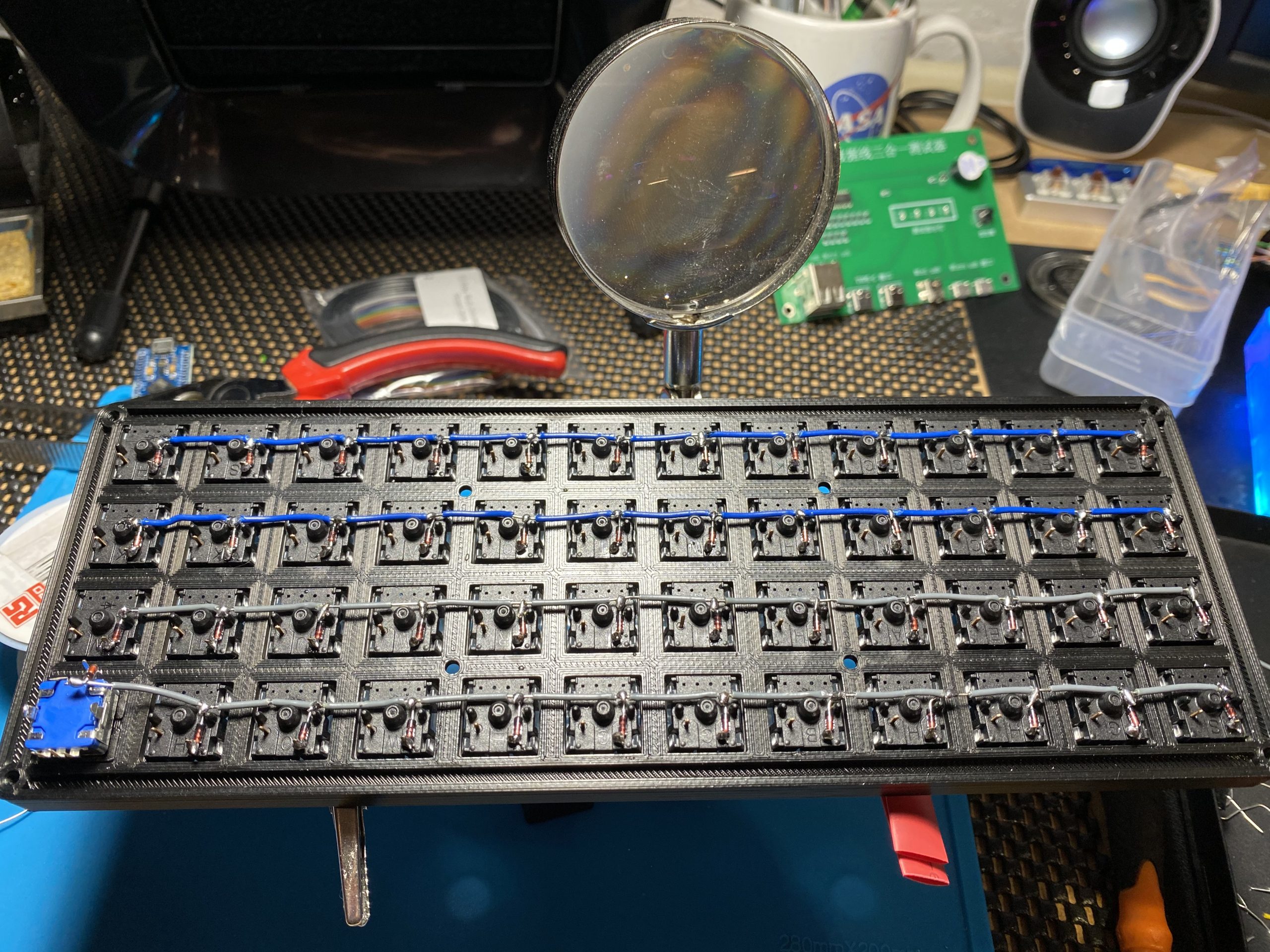 A 3d printed keyboard viewed from the back all siwtches are wired in rows now with a diode between each switch and four rows of wires connecting them.