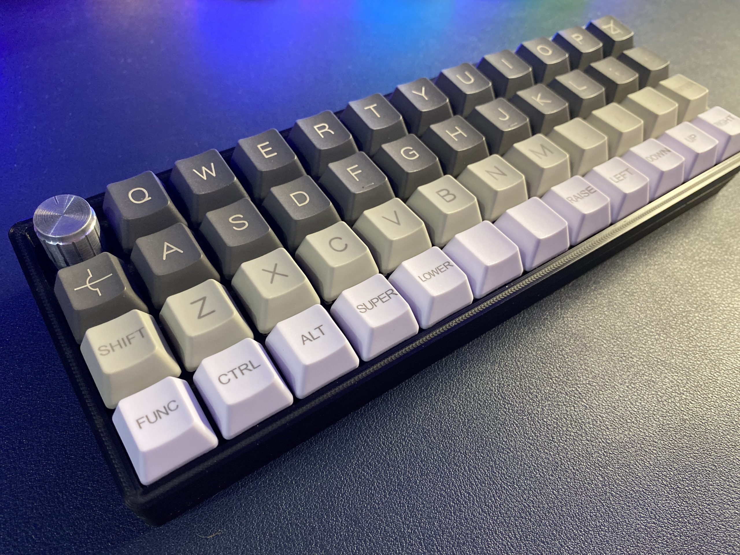 An image of a 40% ortholinear keyboard, with four rows of keys and a rotary encoder where the escape key would be.