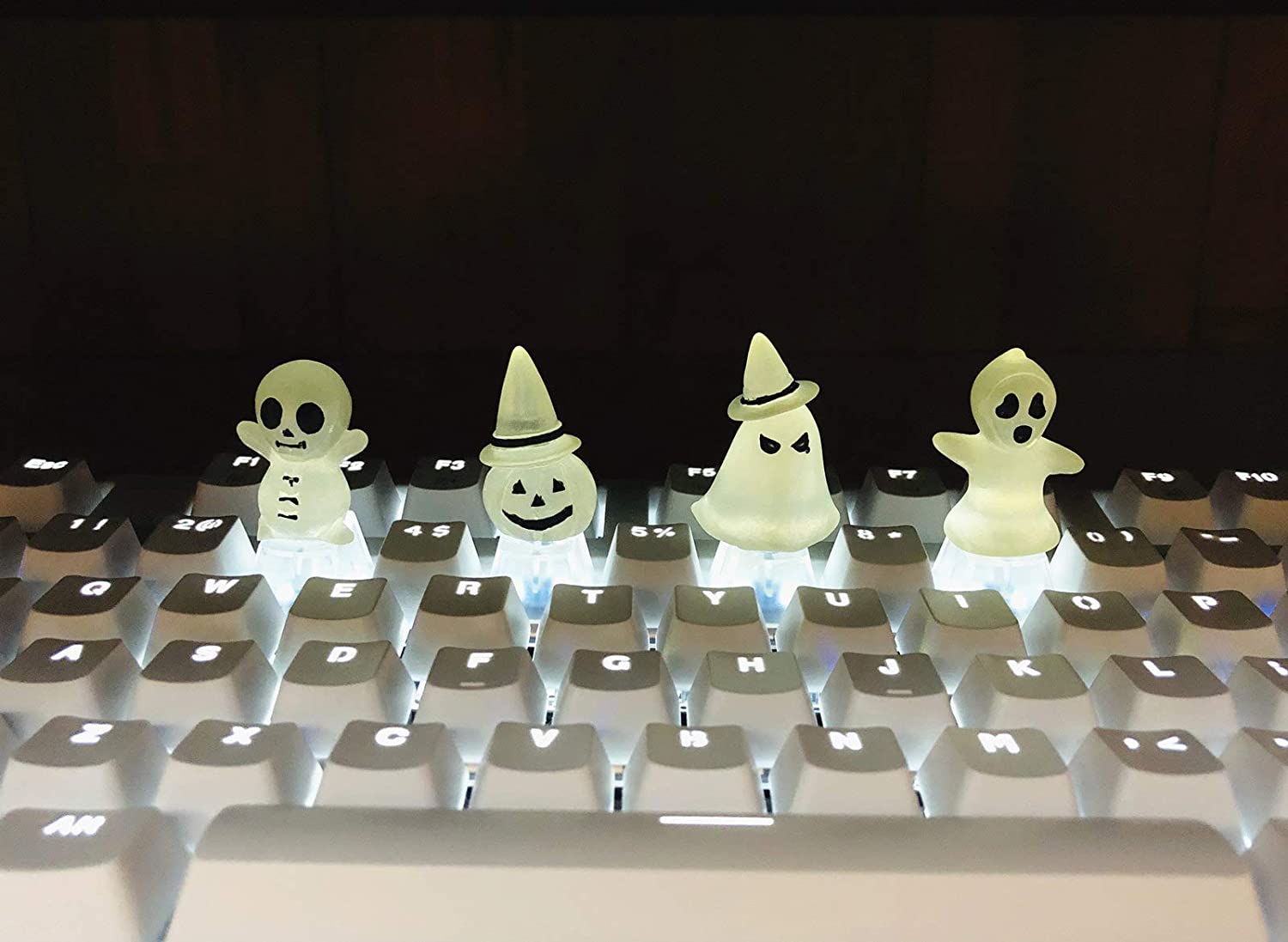 A close picture of a computer keyboard with white keycaps, the keycaps are back lit and 3, 5, 7 and 9 keys have been replaced with keycaps that have translucent ghosts on them.