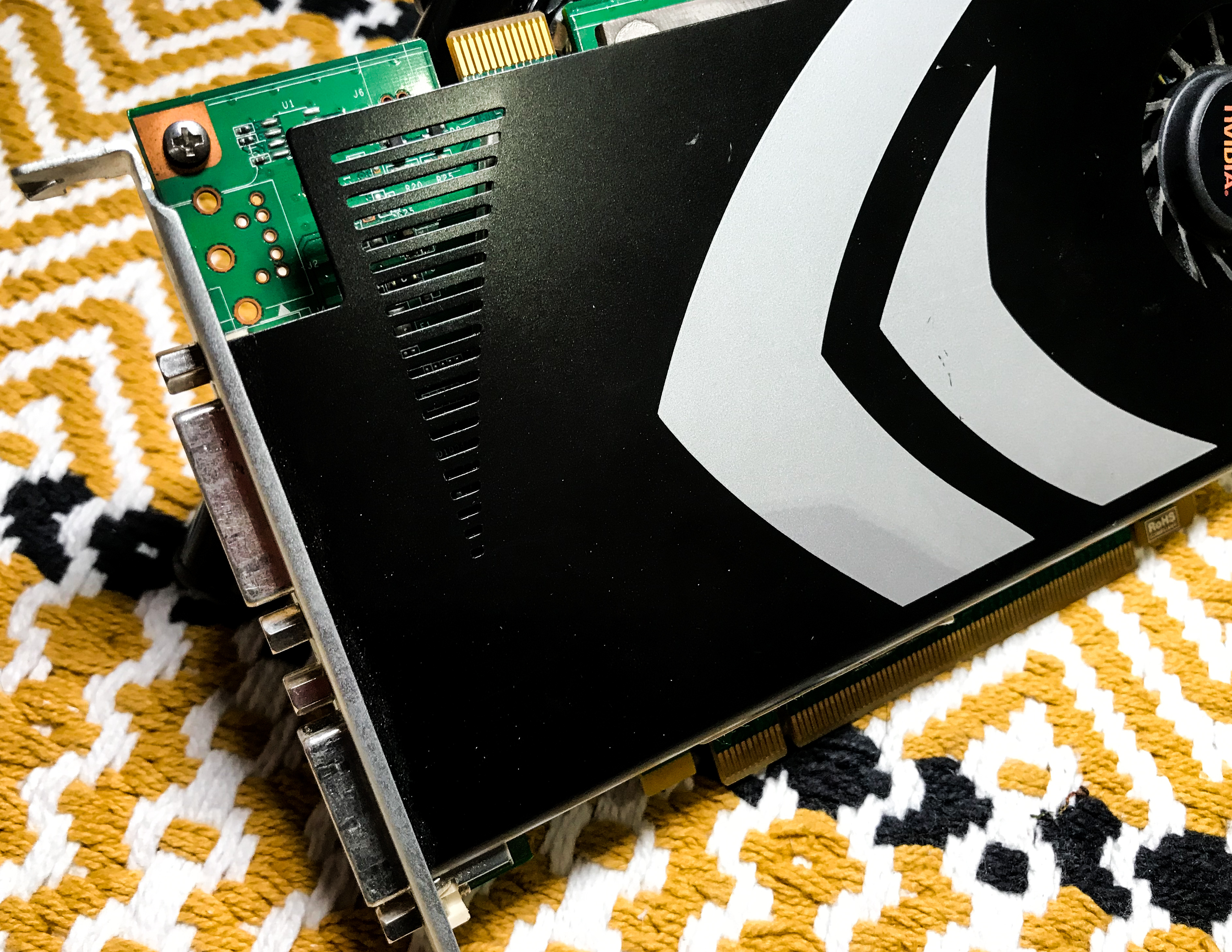 A picture of an Nvidia 8800 GT graphics card sitting on a yellow, black and white rug