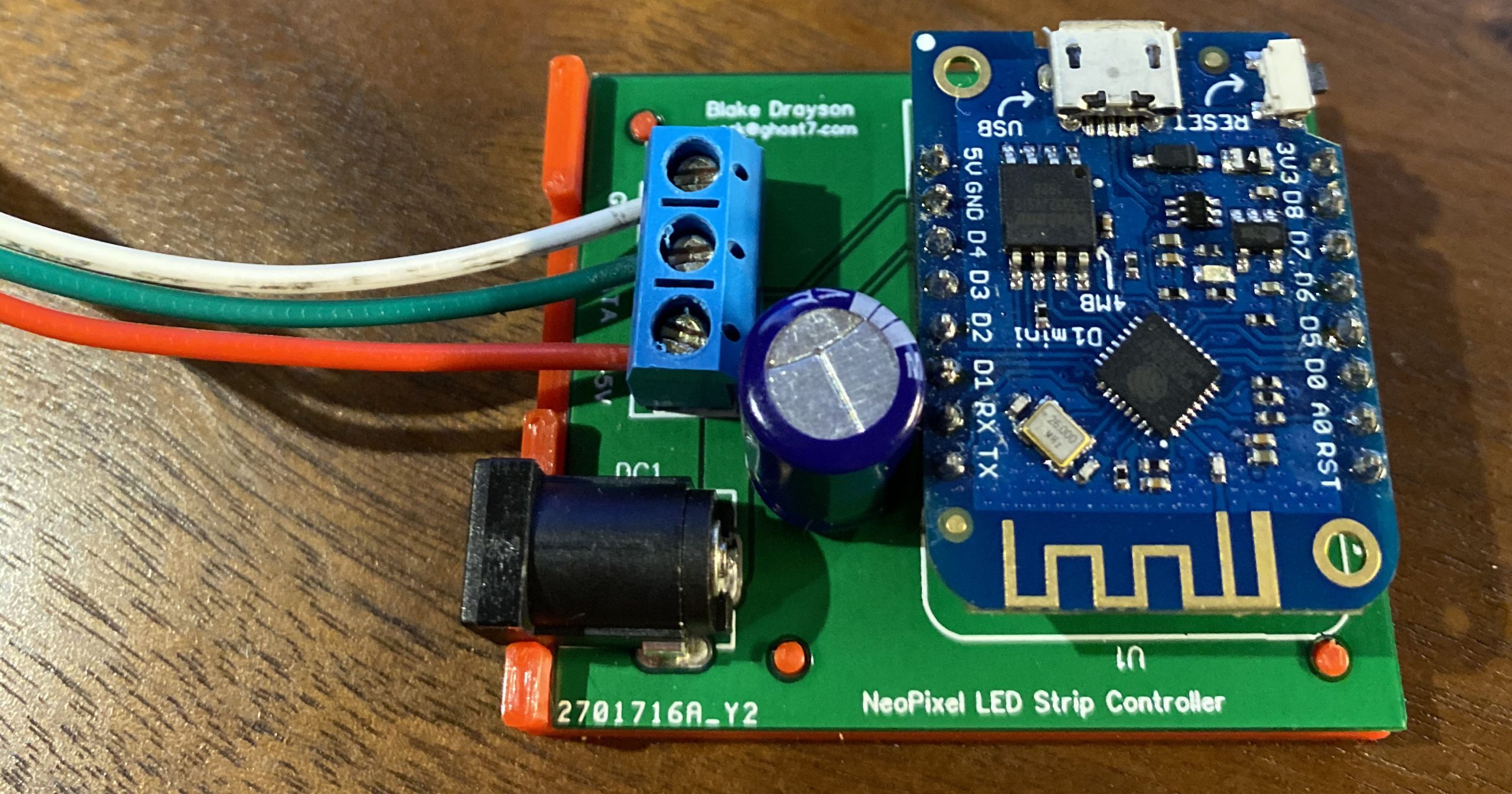 A complete circuit board, containing a esp8266 dev board, a barel jack for 5v power a large capacitor and a terminal connector for cables, all sitting in a 3D printed tray