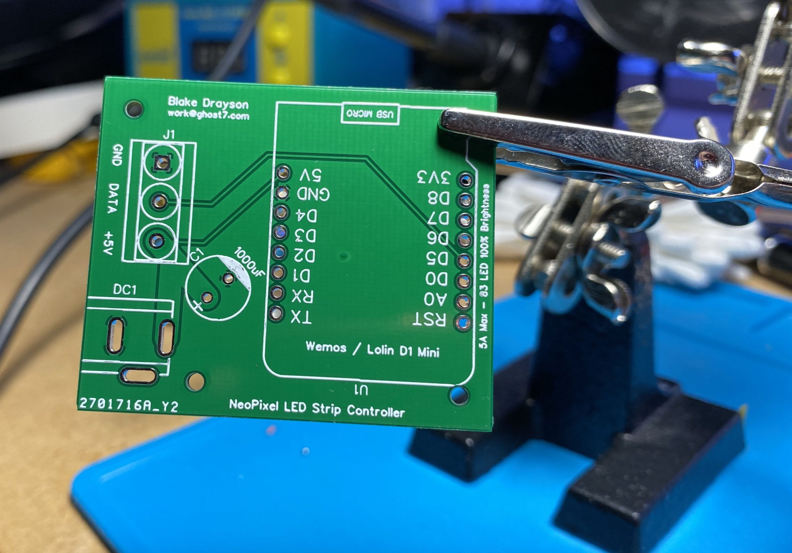 A bare circuit board, being held in the air by a helping hand solder station.